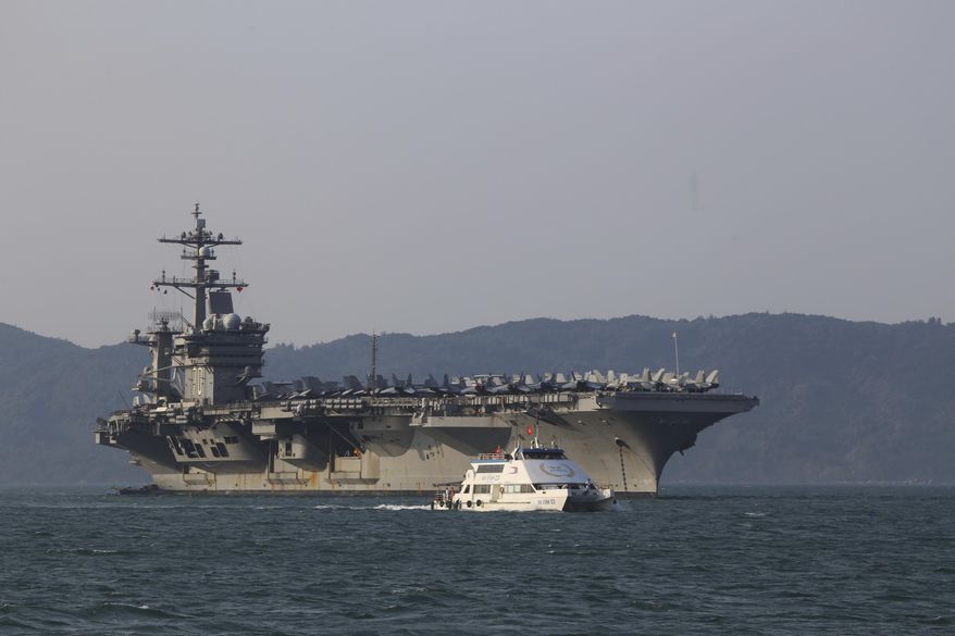 A Vietnamese passenger boat sails past U.S aircraft carrier USS Carl Vinson as it docks in Danang bay, Vietnam on Monday, March 5, 2018. For the first time since the Vietnam War, a U.S. Navy aircraft carrier is paying a visit to a Vietnamese port, seeking to bolster both countries&#39; efforts to stem expansionism by China in the South China Sea. (AP Photo/ Hau Dinh)