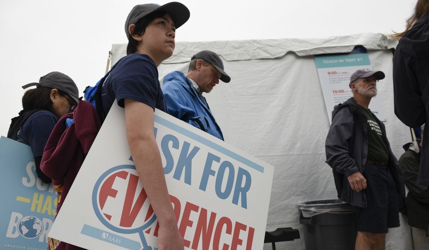 Conall Spaur from Howell, N.J., holds a sign while waiting in line for a teach-in on climate change at the March for Science event in Washington, Saturday, April 22, 2017. Thousands of scientists worldwide left their labs to take to the streets Saturday along with students and research advocates in pushing back against what they say are mounting attacks on science. (AP Photo/Sait Serkan Gurbuz)