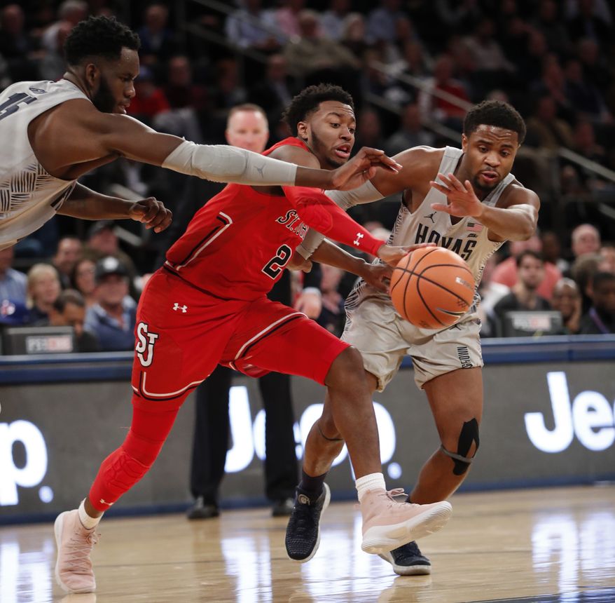 Georgetown's Jessie Govan, left, and Trey Dickerson, right, try to strip the ball from St. John's guard Shamorie Ponds, center, during the second half of an NCAA college basketball game in the first round of the Big East conference tournament, Wednesday, March 7, 2018, in New York. Ponds was the high scorer as St. Johns defeated Georgetown 88-77. (AP Photo/Kathy Willens)