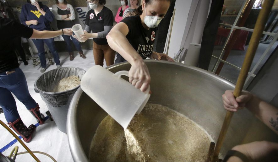 In this Sunday, March 4, 2018, photo, Elizabeth Bove, of Woodstock, Conn., pours grain into a mash mixture while helping brew a batch of beer at Black Pond Brews brewery, in Danielson, Conn. The brewery hosted homebrewers and beer enthusiasts for a Pink Boots Society event in honor of International Women's Day, on March 8. Thousands of women in the beer business and homebrewers in a number of countries are brewing together around that day as a way to raise the profile of women in a male-dominated industry. (AP Photo/Steven Senne)
