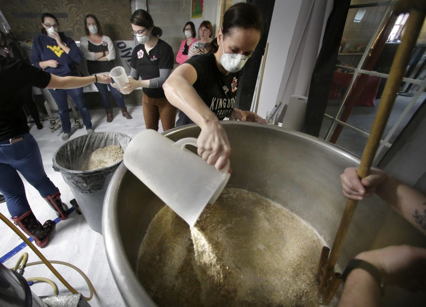 In this Sunday, March 4, 2018, photo, Elizabeth Bove, of Woodstock, Conn., pours grain into a mash mixture while helping brew a batch of beer at Black Pond Brews brewery, in Danielson, Conn. The brewery hosted homebrewers and beer enthusiasts for a Pink Boots Society event in honor of International Women's Day, on March 8. Thousands of women in the beer business and homebrewers in a number of countries are brewing together around that day as a way to raise the profile of women in a male-dominated industry. (AP Photo/Steven Senne)