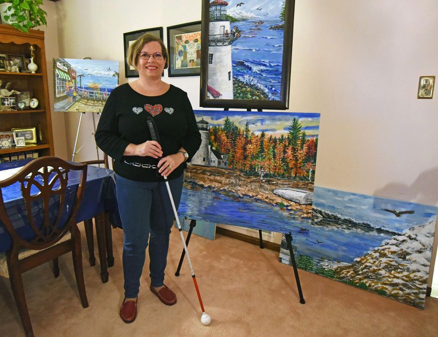 In this undated photo, Diane Krek poses with a few of her paintings at her home in Canonsburg, Pa. Krek started going blind more than 25 years ago.But the Canonsburg woman has not let her visual impairment deter her from helping others through her artwork. (Celeste Van Kirk/Observer-Reporter via AP)