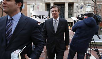 Jason Maloni, left, former Trump campaign chairman Paul Manafort&#x27;s spokesman, left, walks with Paul Manafort, center, as they leave the Alexandria Federal Courthouse after an arraignment hearing on his Eastern District of Virginia charges, in Alexandria, Va., Thursday, March 8, 2018. Behind Manafort protester Bill Christeson holds up a sign that says &amp;quot;traitor.&amp;quot; (AP Photo/Jacquelyn Martin)