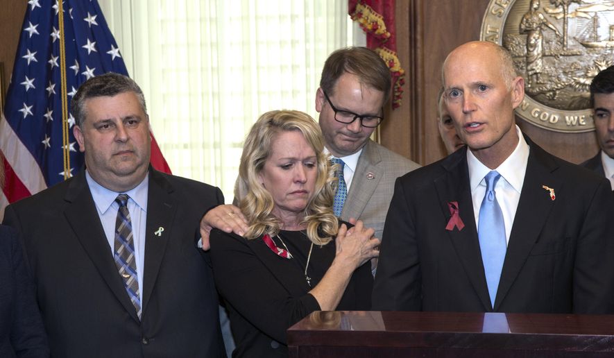 From left, Tony Montalto and wife Jennifer, parents of victim Gina Montalto, 14, and Ryan Petty who's daughter 14-year-old Alaina Petty who were both killed during the Marjory Stonemason Douglas High School shooting, comfort each other as they stand next to Florida Governor Rick Scott before he signs the Marjory Stoneman Douglas Public Safety Act in the Governor's office at the Florida Capital in Tallahassee, Fla., Thursday March 9, 2018. (AP Photo/Mark Wallheiser)