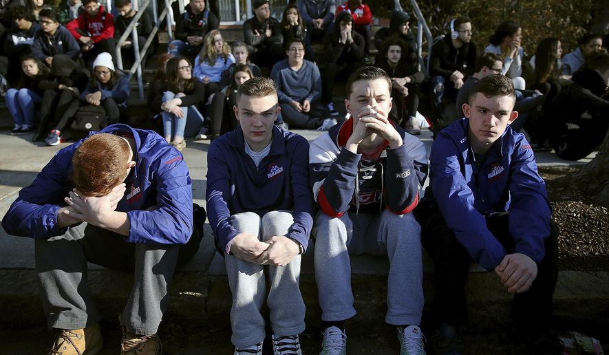 In this Feb. 28, 2018 photo, Somerville High School students sit on the sidewalk on Highland Avenue during a student walkout at the school in Somerville, Mass. A large-scale, coordinated demonstration is planned for Wednesday, March 14, when organizers have called for a 17-minute school walkout nationwide to protest gun violence. (Craig F. Walker/The Boston Globe via AP)