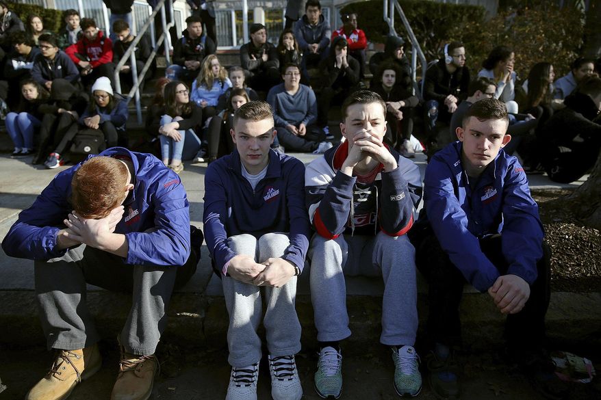 In this Feb. 28, 2018 photo, Somerville High School students sit on the sidewalk on Highland Avenue during a student walkout at the school in Somerville, Mass. A large-scale, coordinated demonstration is planned for Wednesday, March 14, when organizers have called for a 17-minute school walkout nationwide to protest gun violence. (Craig F. Walker/The Boston Globe via AP)