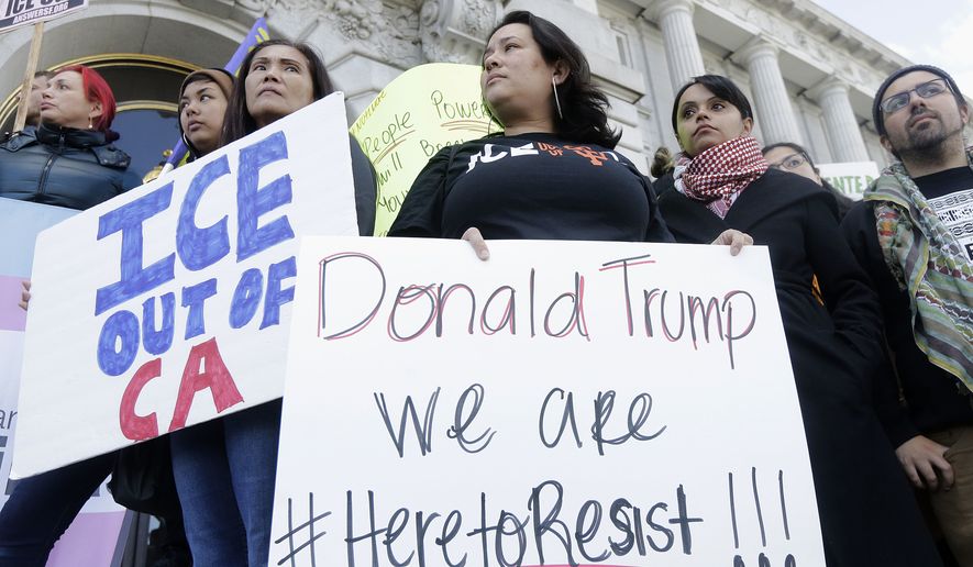 In this Jan. 25, 2017, file photo protesters hold signs as they listen to speakers at a rally outside of City Hall in San Francisco, Calif. Hundreds of bills await action by California lawmakers as the Legislature begins the last week of business this year. Among the issues is the so-called sanctuary state bill, which would restrict state and local aw enforcement agencies from cooperating with federal immigration authorities. (AP Photo/Jeff Chiu, file)