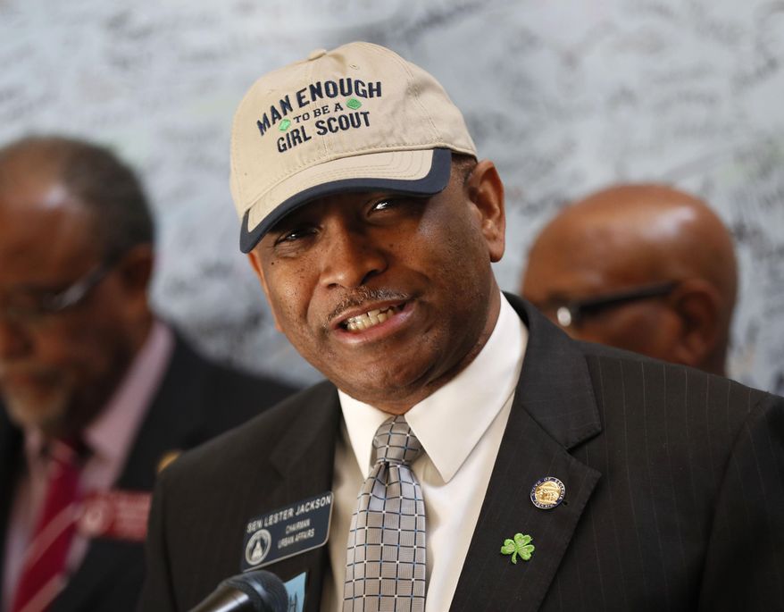 Senator Lester G. Jackson dons a cap supporting the Girl Scouts as he speaks at a press conference in Atlanta Monday,March 12, 2018, joined with other state legislators, where Girl Scouts presented more than 10,000 signatures that support renaming the Talmadge Memorial Bridge in Savanah after the Girl Scouts founder, Juliette Gordon Low. (Bob Andres/Atlanta Journal-Constitution via AP)