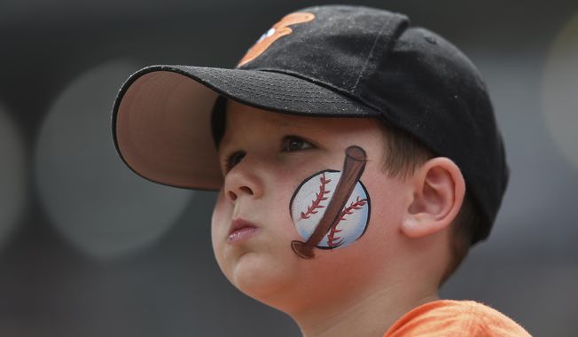 FILE - In this Aug. 6, 2017, file photo, a young baseball fan looks on before the Baltimore Orioles and Detroit Tigers baseball game, in Baltimore. The Orioles have launched a program that will enable kids to attend home games this season free of charge. Fulfilling a child’s request to “take me out to the ballpark” has become a lot cheaper at Camden Yards. Every adult who purchases a regularly-priced upper deck ticket can bring up to two children, age 9 or under. (AP Photo/Gail Burton, File) **FILE**