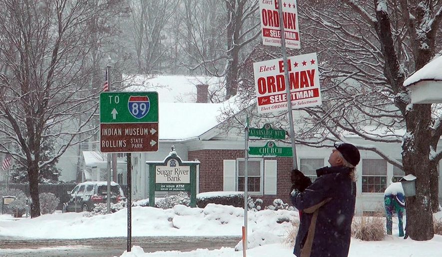 Ed Ordway, a candidate for the Board of Selectman in Warner, N.H., holds a campaign sign outside Town Hall on Tuesday, March 13, 2018. Last year, when a storm also coincided with Town Meeting Day, nearly 80 communities postponed their elections. (AP Photo/Holly Ramer)