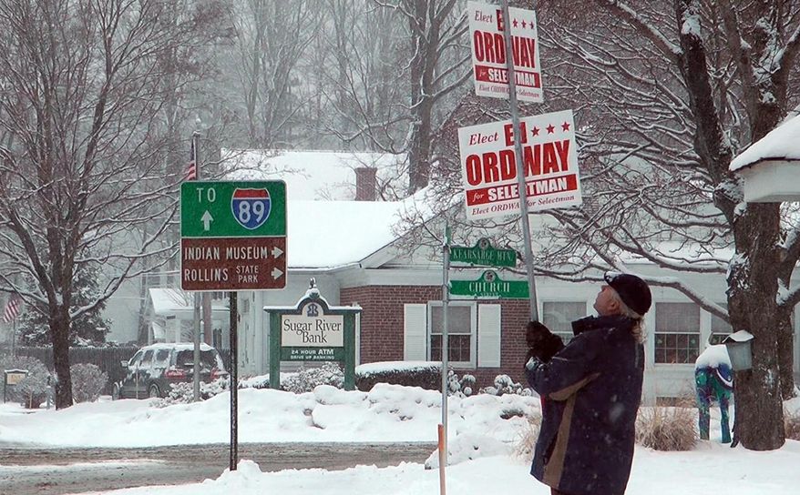 Ed Ordway, a candidate for the Board of Selectman in Warner, N.H., holds a campaign sign outside Town Hall on Tuesday, March 13, 2018. Last year, when a storm also coincided with Town Meeting Day, nearly 80 communities postponed their elections. (AP Photo/Holly Ramer)