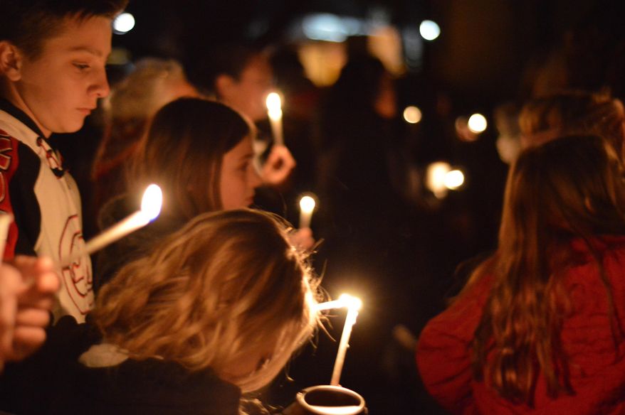 FILE - In this Dec. 7, 2017, file photo, Aztec High School students and area residents gather for a candlelight vigil in Aztec, N.M., after a shooting at the high school. While students across the country plan walkouts to protest gun violence, teens at the New Mexico high school still reeling after two classmates were gunned down in December by an armed intruder have organized a "walk-up" to help unify a campus with varied ideas on school safety. (AP Photo/Russell Contreras, File)