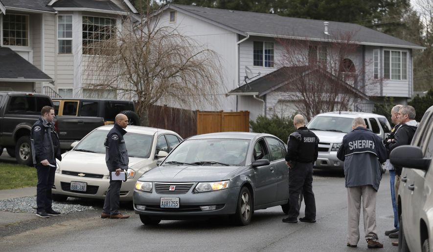 Pierce County Sheriff's Dept. deputies talks to the occupants of a passing car, Tuesday, March 13, 2018, as they stand on a street near a home (not shown) in Spanaway, Wash., where authorities say a member of the U.S. Air Force, who was stationed at Joint Base Lewis-McChord, fatally shot his two young children and their mother before killing himself overnight. (AP Photo/Ted S. Warren)