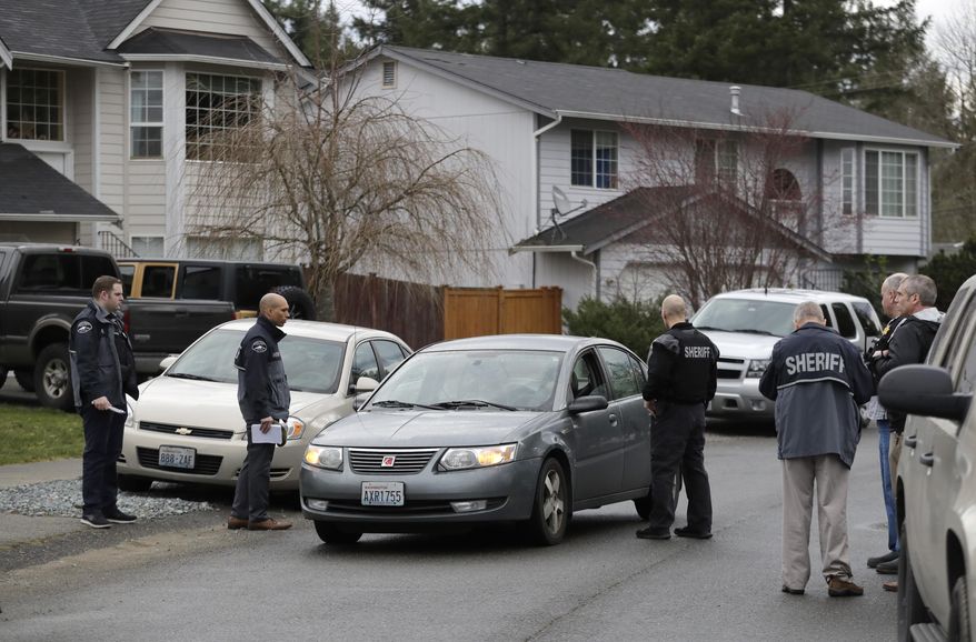 Pierce County Sheriff's Dept. deputies talks to the occupants of a passing car, Tuesday, March 13, 2018, as they stand on a street near a home (not shown) in Spanaway, Wash., where authorities say a member of the U.S. Air Force, who was stationed at Joint Base Lewis-McChord, fatally shot his two young children and their mother before killing himself overnight. (AP Photo/Ted S. Warren)