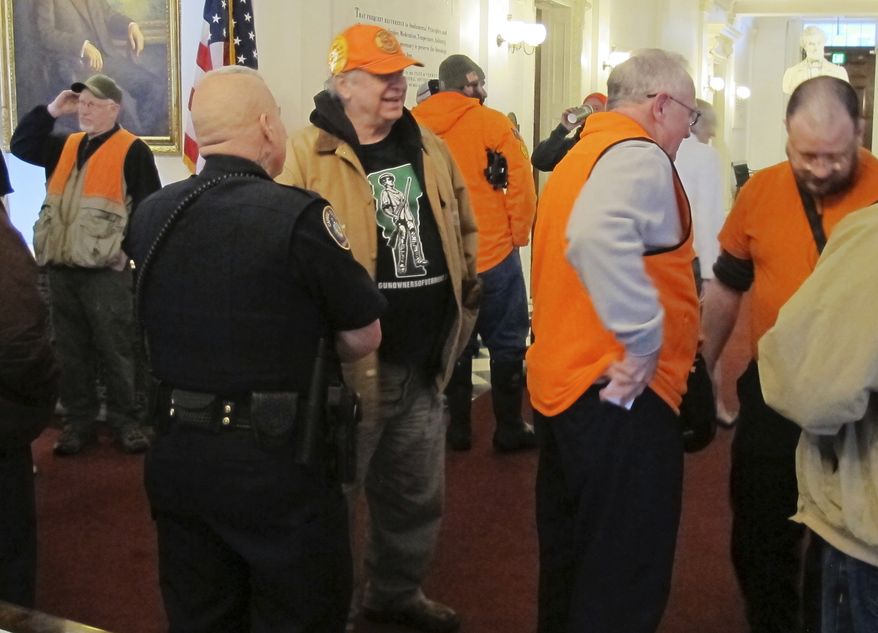 FILE - In this Tuesday, March 13, 2018 file photo, several gun-rights activists wearing blaze orange hunting vests visit the Vermont Statehouse in Montpelier, Vt., where bills are under consideration to place restrictions on gun ownership. A nationwide review of state legislation by The Associated Press suggests the Florida high school shooting may not lead to the sea change in firearms policy that gun-control advocates had desired. People on both sides of the debate are watching developments in gun-friendly Vermont, where Republican Gov. Phil Scott abandoned his stance against gun control after police arrested an 18-year-old man allegedly plotting a mass shooting at a high school. (AP Photo/Wilson Ring, File)