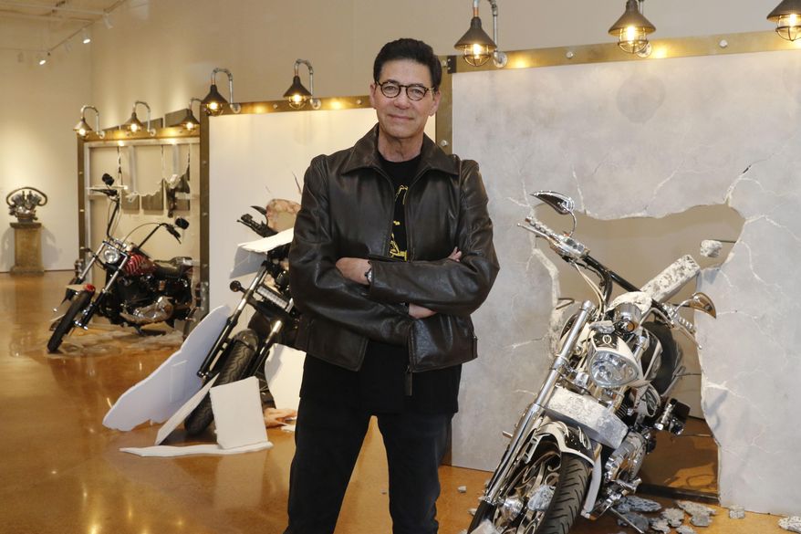 In a Monday, March 5, 2018 photo, Bobby Haas poses for a portrait in front of three sculptures, titled; "Through The Wall", at the Haas Moto Museum & Sculpture Gallery in Dallas. He has assembled a collection of over 100 motorcycles and will open on April 11, 2018 in the Design District. (David Woo/The Dallas Morning News via AP)