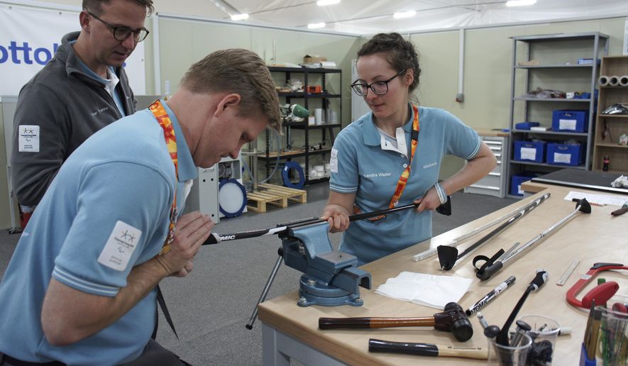 In this March 13, 2018, photo, John Spillar, second from left, one of Ottobock's American specialists who previously worked at the Parapan American Games and Invictus Games, works with an unidentified his colleague as Peter Franzel, left top, a director at Ottobock, watches at Pyeongchang's athletes' village in Pyeongchang, South Korea. At a white warehouse on a corner of Pyeongchang’s athletes’ village, a team of technicians hustle around the clock to carve, weld and sew ripped things near piles of hands, feet and bionic knees. (AP Photo/Kim Tong-hyung)