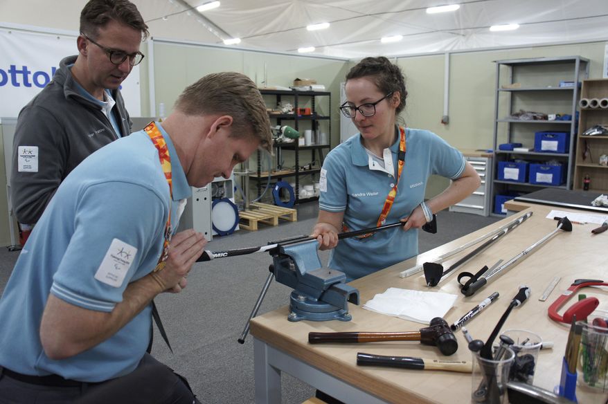 In this March 13, 2018, photo, John Spillar, second from left, one of Ottobock's American specialists who previously worked at the Parapan American Games and Invictus Games, works with an unidentified his colleague as Peter Franzel, left top, a director at Ottobock, watches at Pyeongchang's athletes' village in Pyeongchang, South Korea. At a white warehouse on a corner of Pyeongchang’s athletes’ village, a team of technicians hustle around the clock to carve, weld and sew ripped things near piles of hands, feet and bionic knees. (AP Photo/Kim Tong-hyung)