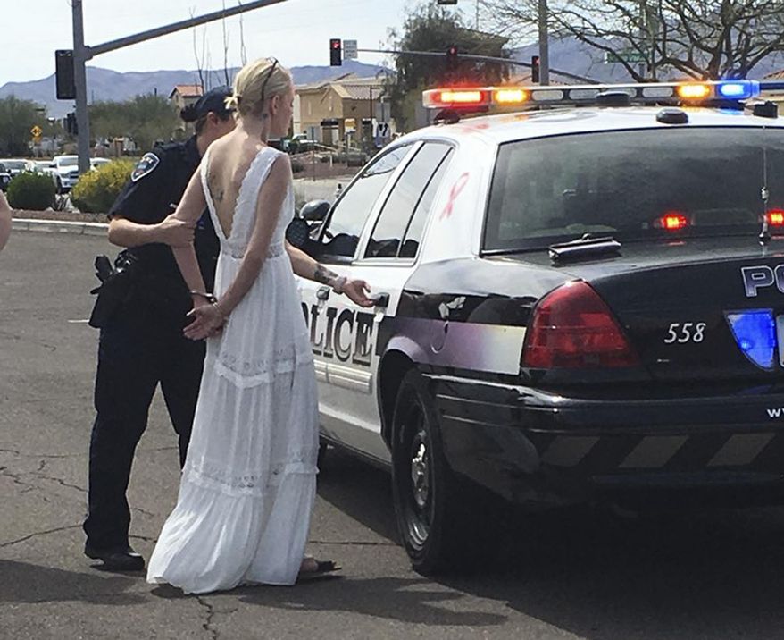 FILE--This March 12, 2018, file photo provided by the Marana Police Department, in Arizona, shows 32-year-old Amber Young during her arrest on suspicion of impaired driving in Marana, Ariz. Young, who was photographed wearing what appeared to be a wedding dress during her impaired-driving is disputing a claim by police that she was taken into custody as she was headed to her wedding. (Marana Police Department via AP, file)