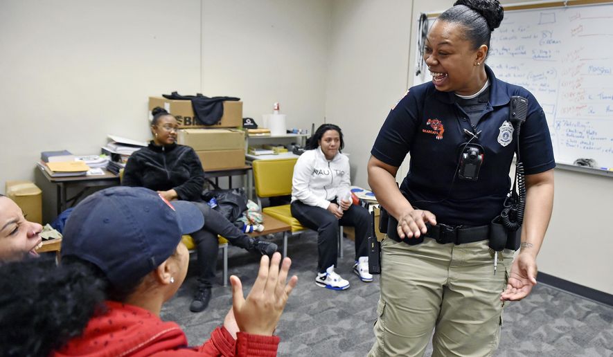 In a Thursday, March 8, 2018 photo, York City School District police officer Britney Brooks shares a laugh with seniors organizing a fundraiser event at William Penn Senior High School in York, Pa. The York City School District is the only one in York County with its own police department. Officers, who have the power of arrest, operate on a community policing ideology to prevent incidents rather than react to them.  (Chris Dunn/York Daily Record via AP)