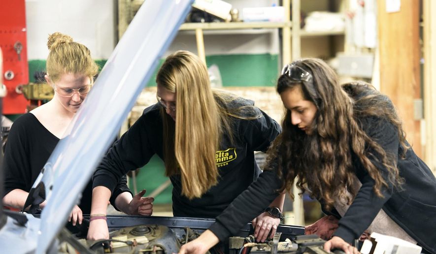 In this Monday, March 5, 2018 photo from left to right, Myers Park auto mechanics students Ann Payne, Elizabeth Montgomery and Miley Chavez reattach a car part during class at Myers Park High School in Charlotte, N.C. The school is pushing classes that prepare students for hands-on careers. (John D. Simmons /The Charlotte Observer via AP)