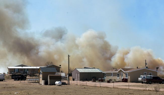 Smoke from a wildfire, named the Carson Midway wildfire, billows behind homes in Hanover, Colo., Friday March 16, 2018. (Dougal Brownlie/The Gazette via AP)