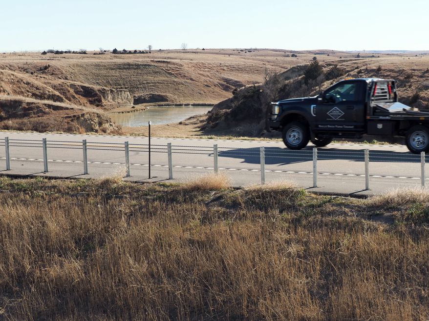 In this Tuesday, Dec. 5, 2017 photo, a vehicle drives near an area where water diverted from the Platte River would flow from a canal on the near side of Nebraska Highway 23 into the canyons on the far side of the road and into Turkey Creek in Smithfield, Neb. (David Hendee/Omaha World-Herald via AP)