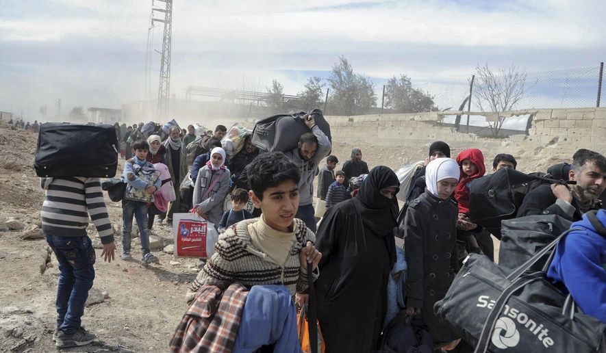 In this photo released by the Syrian official news agency SANA, civilians carry their belongings as they flee from fighting between Syrian government forces and rebels in Hamouria in eastern Ghouta, a suburb of Damascus, Syria, on Thursday, March. 15, 2018. Thousands streamed out of Syria's besieged, opposition-held enclave of eastern Ghouta on Thursday, crossing on foot and in pick-up trucks and tractors to government-held territory near the capital, Damascus, according to footage on state-run Syrian television. (SANA via AP)