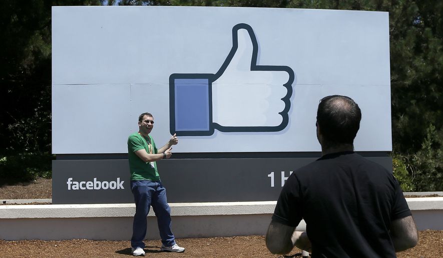 FILE - In this June 11, 2014, file photo, a man poses for photographs in front of the Facebook sign on the Facebook campus in Menlo Park, Calif. Facebook reports quarterly financial results on Wednesday, July 29, 2015. (AP Photo/Jeff Chiu, File)