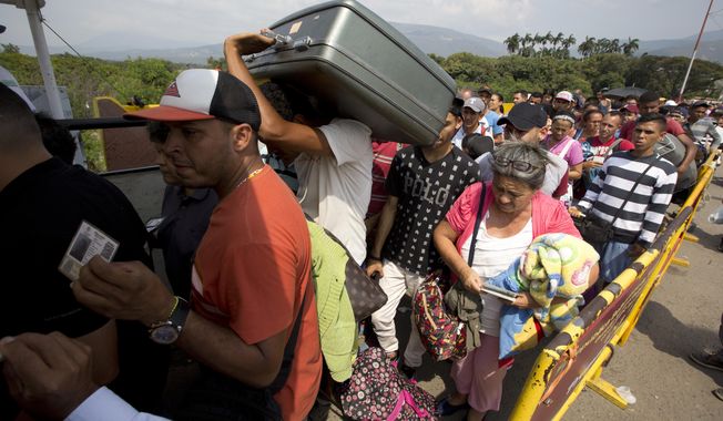 FILE - In this Feb. 21, 2018 file photo, Venezuelans cross the International Simon Bolivar bridge into Cucuta, Colombia, as rising numbers of Venezuelans are fleeing in a burgeoning refugee crisis that could soon match the flight of Syrians from the war-torn Middle East. The Trump administration is providing $2.5 million in emergency food and medicine to Venezuelan migrants in Colombia in the U.S.’ first action to alleviate a burgeoning humanitarian crisis that has reverberated across Latin America, according to a USAID statement on Tuesday, March 20, 2018. (AP Photo/Fernando Vergara, File)