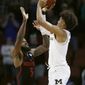 FILE - This March 17, 2018 file photo shows Michigan guard Jordan Poole shooting a 3-point basket over Houston guard Corey Davis Jr. (5) at the buzzer to win an NCAA men&#39;s college basketball tournament second-round game in Wichita, Kan. Michigan won 64-63. Poole’s buzzer beater came with one good eye. The Michigan freshman had protective glasses when he met with reporters Tuesday, March 20, 2018 less than 72 hours after his last-second 3-pointer gave the Wolverines a victory over Houston and sent them to the Sweet 16. Poole said he was poked in the right eye during the game. (AP Photo/Charlie Riedel)