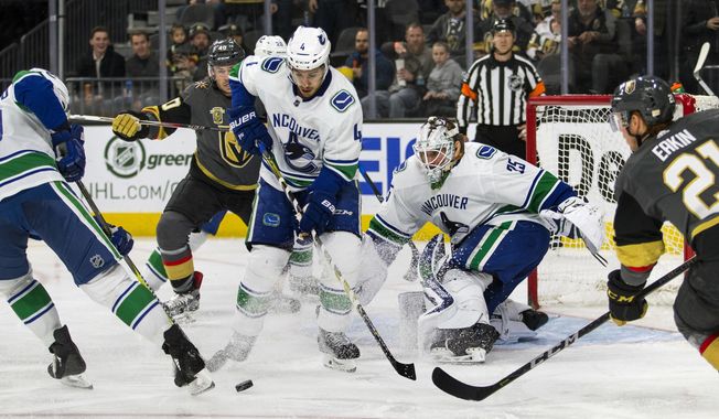 Vancouver Canucks defenseman Michael Del Zotto (4) helps to defend the net with help from goaltender Jacob Markstrom (25) as Vegas Golden Knights center Cody Eakin (21) moves in during the second period of an NHL hockey game Tuesday, March 20, 2018, in Las Vegas. (AP Photo/L.E. Baskow)