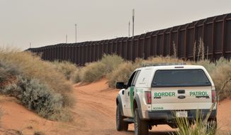 FILE - In this Jan. 4, 2016 file photo, a U.S. Border Patrol agent drives near the U.S.-Mexico border fence in Santa Teresa, N.M. A coalition of environment groups is seeking to stop work to replace existing vehicle barriers along the U.S.-Mexico border in southern New Mexico. The groups filed a lawsuit in U.S. District Court on Thursday, March 22, 2018, claiming the U.S. Department of Homeland Security does not have authority to waive environmental laws as a way to speed construction along a 20-mile stretch near the Santa Teresa port of entry.(AP Photo/Russell Contreras, File)