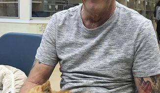 This March 2018 photo made available by the Humane Society of the Treasure Coast in Palm City, Fla., shows Perry Martin with his cat T2. Martin lost his pet during Hurricane Jeanne 14 years ago. Martin had T2 implanted with a microchip in 2002. He never heard any news about his missing pet until a Martin County Animal Services officer called him to tell him T2 was in a shelter in Palm City. (Vanessa Aguirre/Humane Society of the Treasure Coast via AP)
