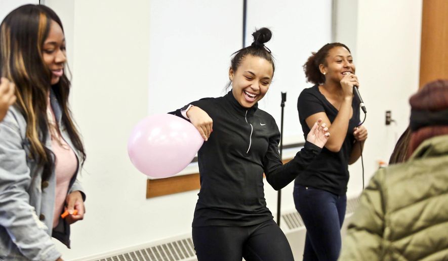 In this March 7, 2018 photo, Sister Circle's Casie Pierce, center, has fun during Battle of the Sexes on the campus of Millikin University in Decatur, Ill. The organization was established to address the needs and concerns of women, specifically underrepresented women, focusing on issues such as academics, career development, standards of beauty, sexuality, and relationships. (Clay jackson/Herald & Review via AP)