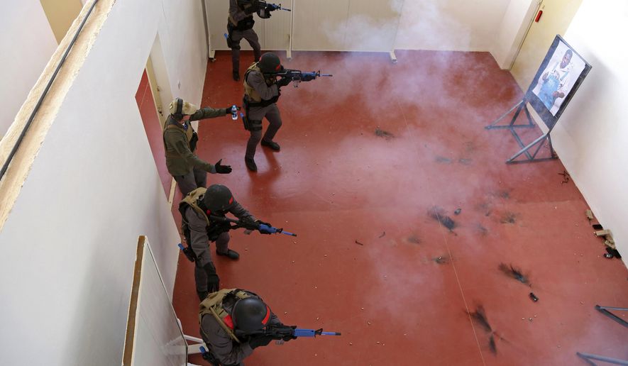 In this Sunday, March 18, 2018 photo, members of a Tunisian police commando unit storm a room during a drill at the Jordan Gendarmerie Training Academy, in al-Swaqa, about 44 miles (70 km) south of Amman, Jordan. The U.S.-funded center, which formally opens Thursday, will conduct counter-terrorism training for law enforcement agencies from a pool of 56 eligible partner countries. (AP Photo/Raad Adayleh)