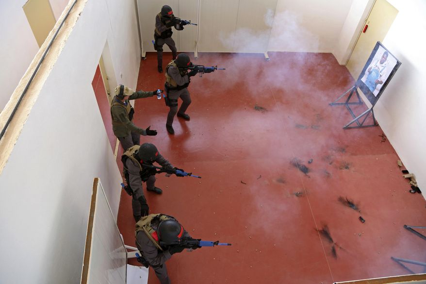 In this Sunday, March 18, 2018 photo, members of a Tunisian police commando unit storm a room during a drill at the Jordan Gendarmerie Training Academy, in al-Swaqa, about 44 miles (70 km) south of Amman, Jordan. The U.S.-funded center, which formally opens Thursday, will conduct counter-terrorism training for law enforcement agencies from a pool of 56 eligible partner countries. (AP Photo/Raad Adayleh)