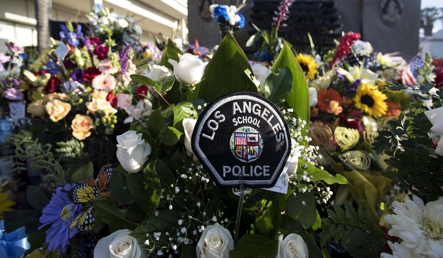 In this March 11, 2018 photo, flowers are displayed for a candlelight vigil for Greggory Casillas at the Pomona Police Department in Pomona, Calif. A man suspected of shooting two California police officers, killing Casillas, was arrested Saturday after barricading himself in an apartment and holding a SWAT team at bay, authorities said. (Cindy Yamanaka/Los Angeles Daily News via AP)