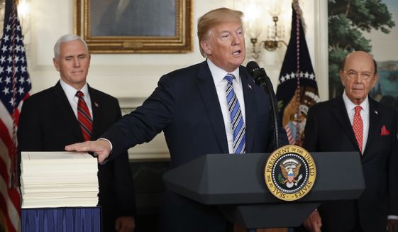 President Donald Trump reaches to touch a copy of the $1.3 trillion spending bill as he speaks in the Diplomatic Room of the White House in Washington, Friday, March 23, 2018, as Vice President Mike Pence, left, and Commerce Secretary Wilbur Ross watch. (AP Photo/Pablo Martinez Monsivais)