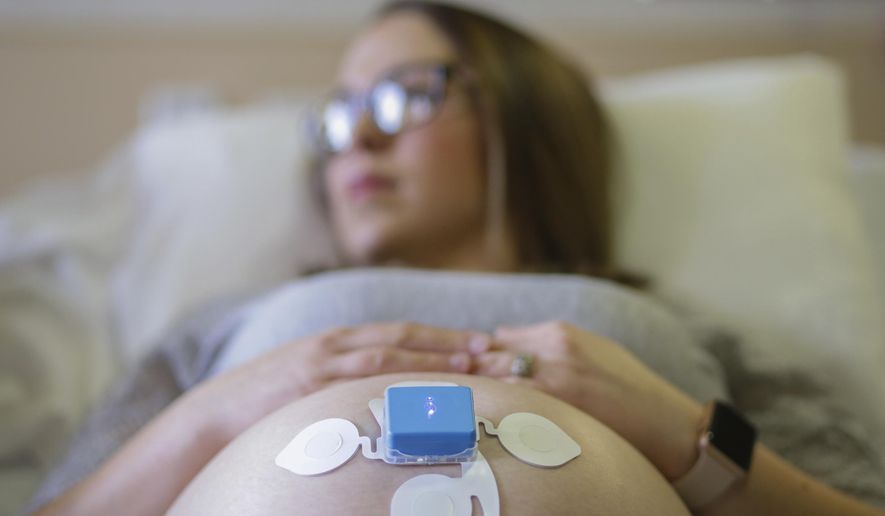 In this Wednesday, Feb. 21, 2018 photo, Serena Esplin, a labor and delivery nurse, wears the Monica Novii, a wireless heart rate and contraction monitor, at East Idaho Regional Medical Center in Idaho Falls, Idaho. The wireless system allows tracking of the heart rate of both the mother and baby as well as uterine contractions in a small package that also allows the mother to be more mobile than with other wired systems. (John Roark/The Idaho Post-Register via AP)