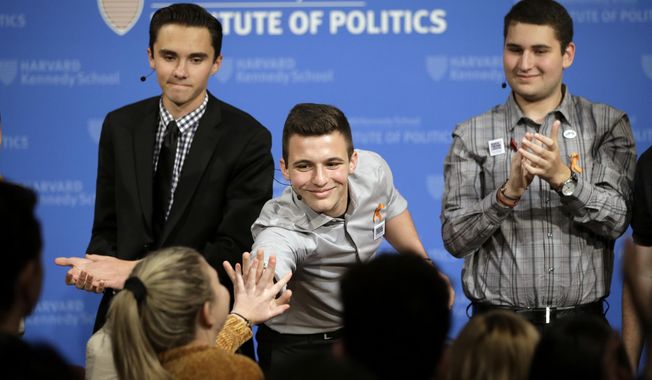 FILE - In this March 20, 2018, file photo, Marjory Stoneman Douglas High School student Cameron Kasky, center, reaches out to clasp hands with Jaclyn Corin, below left, while David Hogg, top left, and Alex Wind, right, applaud at the conclusion of a panel discussion about guns at the Harvard Kennedy School Institute of Politics in Cambridge, Mass.   (AP Photo/Steven Senne, File)