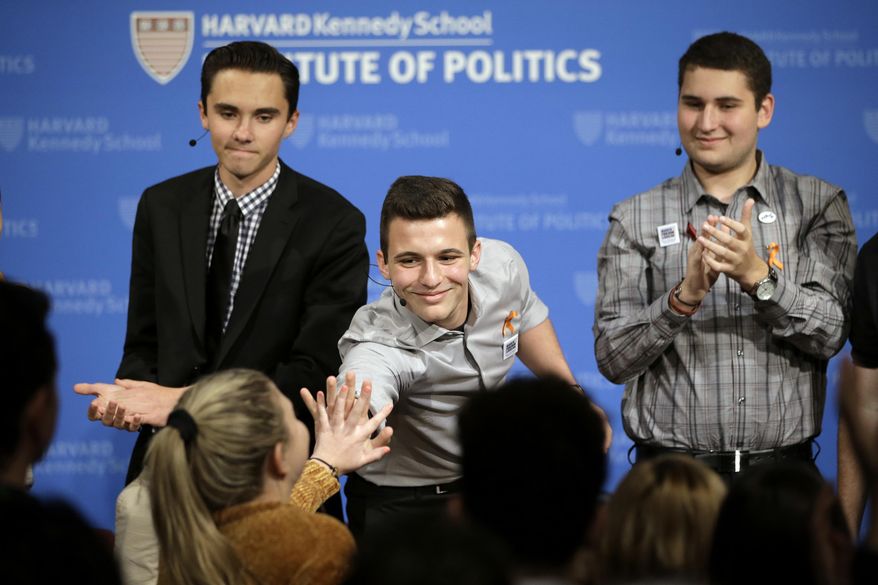 FILE - In this March 20, 2018, file photo, Marjory Stoneman Douglas High School student Cameron Kasky, center, reaches out to clasp hands with Jaclyn Corin, below left, while David Hogg, top left, and Alex Wind, right, applaud at the conclusion of a panel discussion about guns at the Harvard Kennedy School Institute of Politics in Cambridge, Mass. (AP Photo/Steven Senne, File)