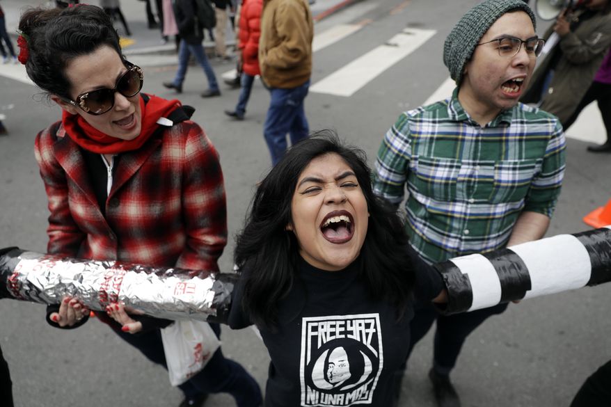 FILE--In this Feb. 28, 2018, file photo, demonstrators, including, Valeria Suarez, center, and Gerardo Gomez, right, yell slogans as they block an intersection outside of the Immigration and Customs Enforcement offices in San Francisco. Texas and more than a dozen other states led by Republican governors got behind the Trump administration on Monday, March 26, 2018, in its lawsuit over California's so-called sanctuary laws that protect people in the U.S. illegally. (AP Photo/Marcio Jose Sanchez, file)