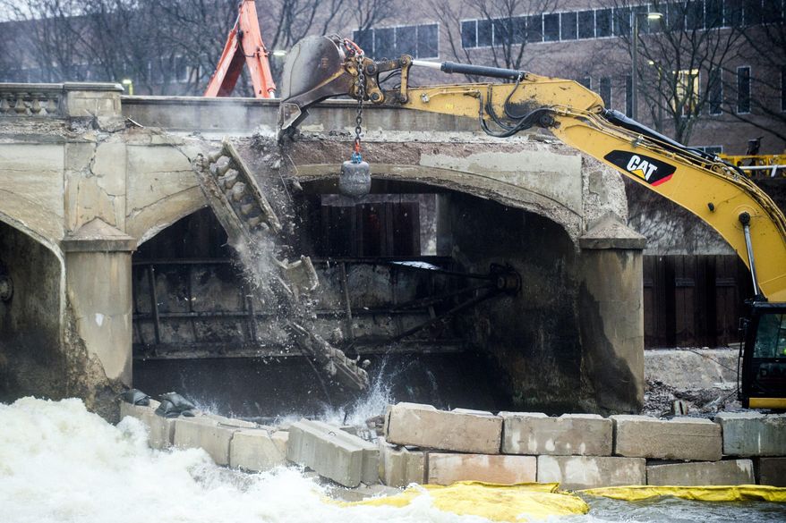 Pieces of concrete fall as a crew works to demolish the Hamilton Dam, Tuesday, March 27, 2018 in downtown Flint, Mich.. The demolition was initially scheduled for 2017, but it was moved back because the city needed to wait for Consumers Energy to finish dredging and capping the Flint River. The dredging of the Flint River was completed in late fall of 2017. (Jake May/The Flint Journal-MLive.com via AP)