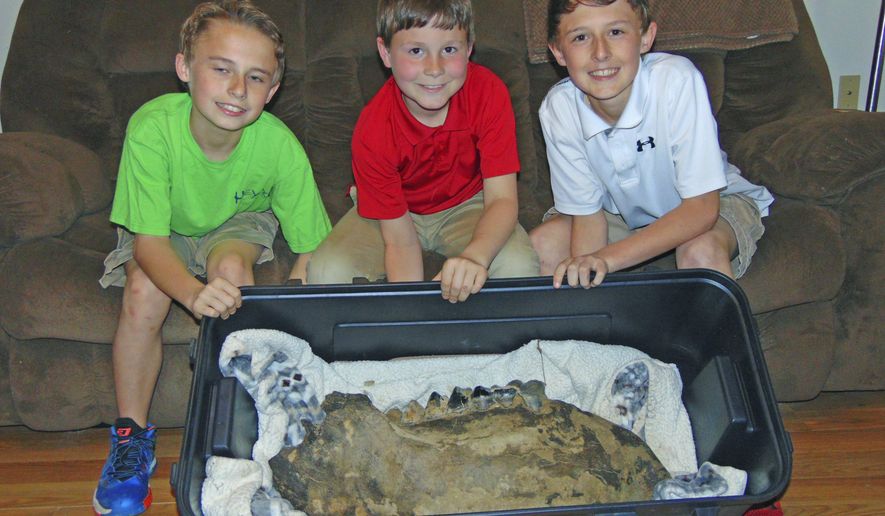 In this Monday, March 19, 2018 photo, Shawn Sellers, left, Michael Mahalitc and Caid Sellers, display the lower left jawbone of a mastodon they found in a plowed up area of their family's property in the Bovina area in Vicksburg, Miss. (John Surratt/The Vicksburg Post via AP)
