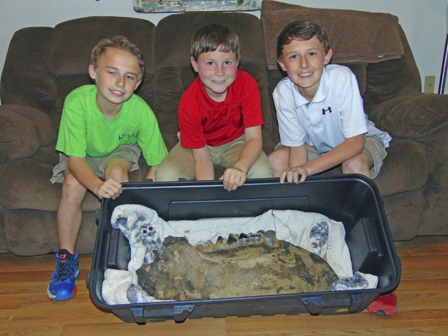 In this Monday, March 19, 2018 photo, Shawn Sellers, left, Michael Mahalitc and Caid Sellers, display the lower left jawbone of a mastodon they found in a plowed up area of their family's property in the Bovina area in Vicksburg, Miss. (John Surratt/The Vicksburg Post via AP)