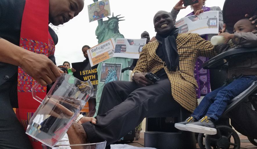 The Rev. Reuben Eckles washes Congolese refugee Beni Dedieu Luzau's feet on Wednesday. The Interfaith Immigration Coalition organized the ceremonial foot washing with refugees in front of the White House. (Julia Airey/The Washington Times)