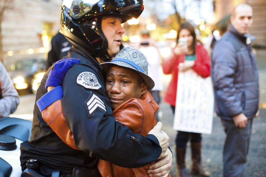 FILE - In this Nov. 25, 2014, file photo provided by Johnny Nguyen, Portland police Sgt. Bret Barnum, left, and Devonte Hart, 12, hug at a rally in Portland, Ore., where people had gathered in support of the protests in Ferguson, Mo. Authorities have said two women and three children were killed Monday, March 26, 2018, when their SUV fell from a cliff along Pacific Coast Highway in Mendocino County. Hart is one of the three other children still missing after the vehicle fell off a cliff. He had gained fame when this picture of him hugging the white police officer during the protest went viral. (Johnny Huu Nguyen via AP, File)