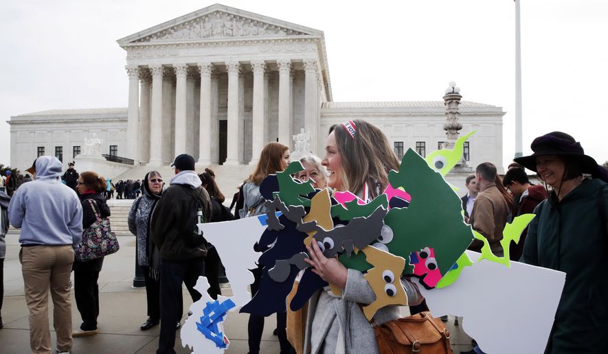 In this file photo, Ashley Oleson, with the League of Women Voters of Maryland, carries signs of Maryland's districts, as nonpartisan groups against gerrymandering protest in front of the Supreme Court, Wednesday, March 28, 2018, in Washington where the court will hear arguments on a gerrymandering case. (AP Photo/Jacquelyn Martin) **FILE**