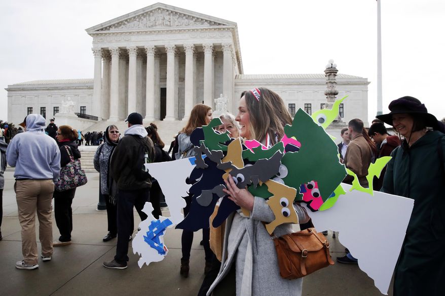 In this file photo, Ashley Oleson, with the League of Women Voters of Maryland, carries signs of Maryland's districts, as nonpartisan groups against gerrymandering protest in front of the Supreme Court, Wednesday, March 28, 2018, in Washington where the court will hear arguments on a gerrymandering case. (AP Photo/Jacquelyn Martin) **FILE**